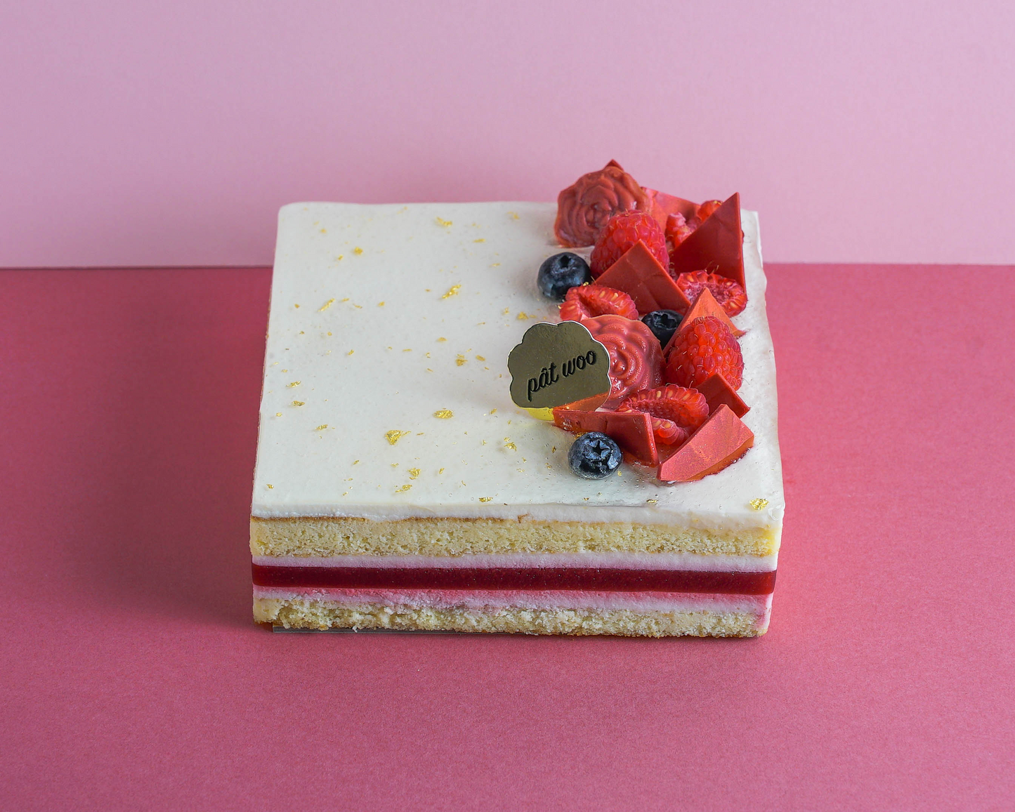 Tri-flavoured layered cake decorated with raspberries, blueberries and chocolate pieces. Layered with raspberry jelly, rose-scented almond sponge and lychee mousse.